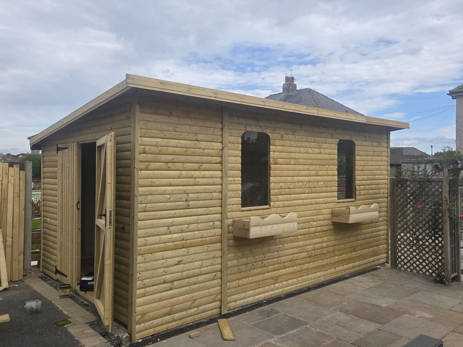 Finished timber garage and workshop with log lap cladding, windows and window boxes