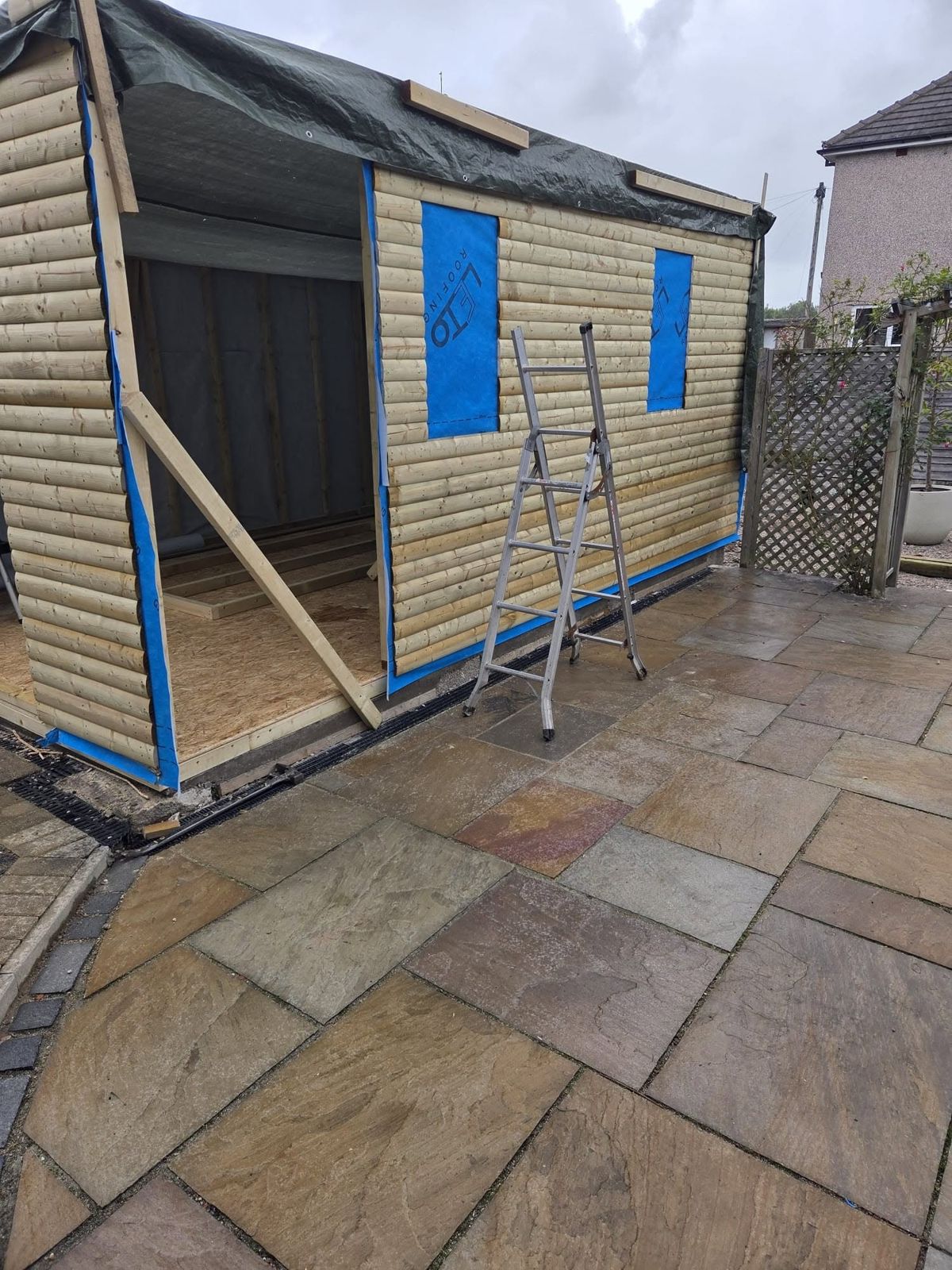 Log lap cladding being fixed to the side of the new garage