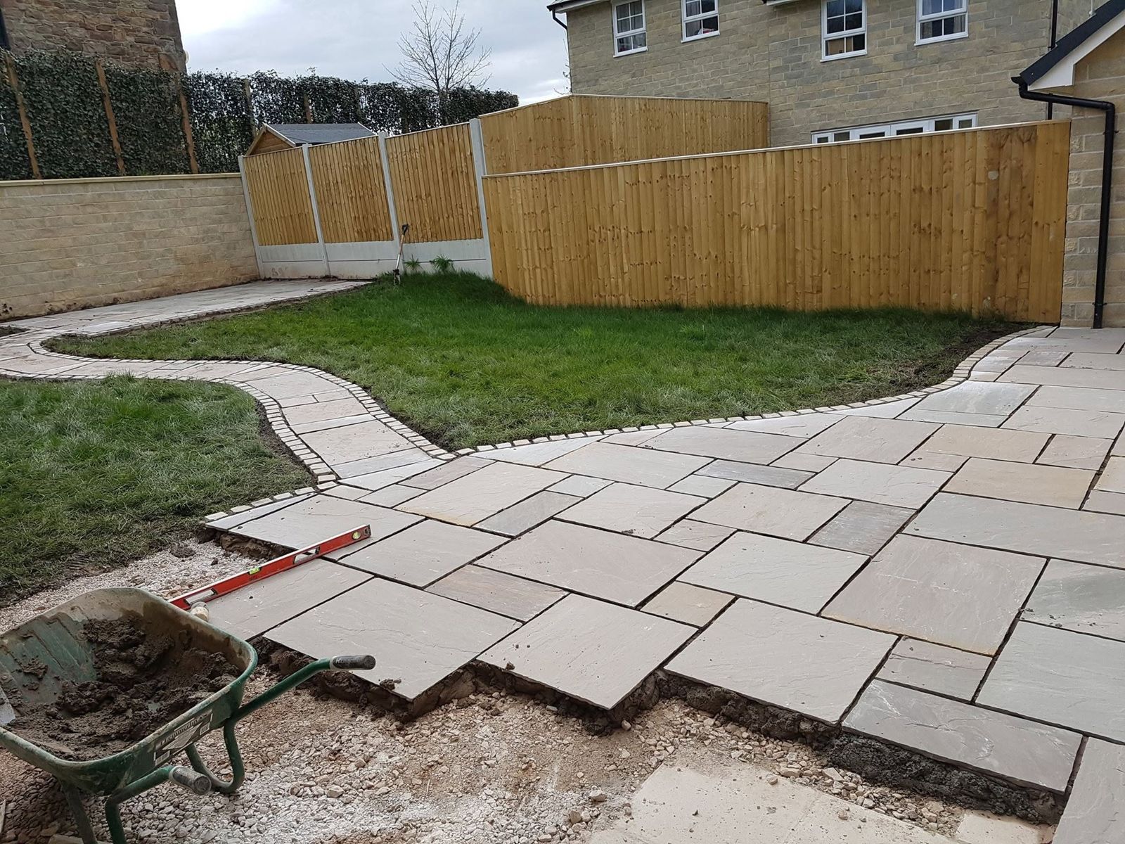 Patio and curved path taking shape beside new fencing