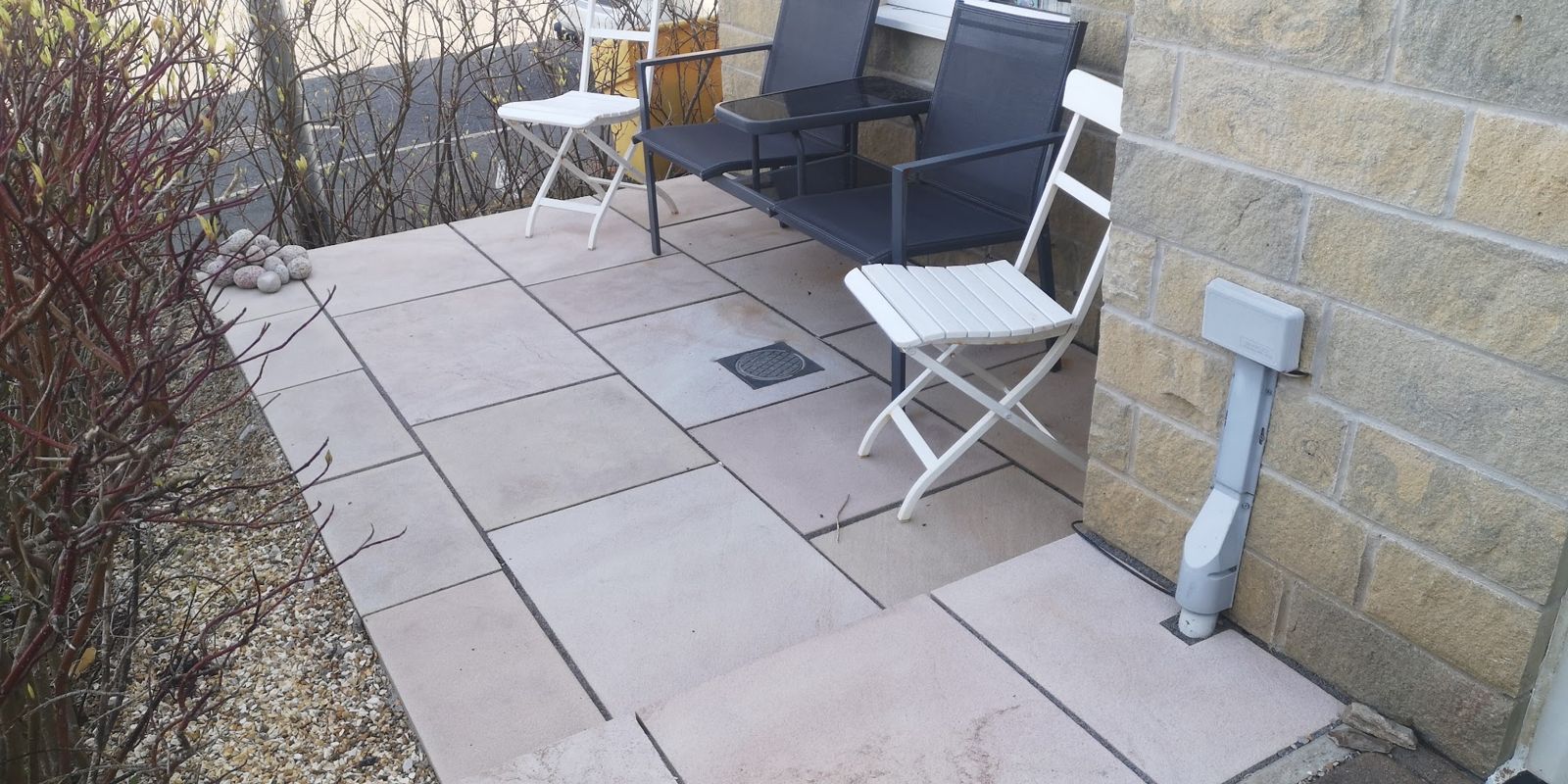 Stone patio with a table and chairs beside a stone wall