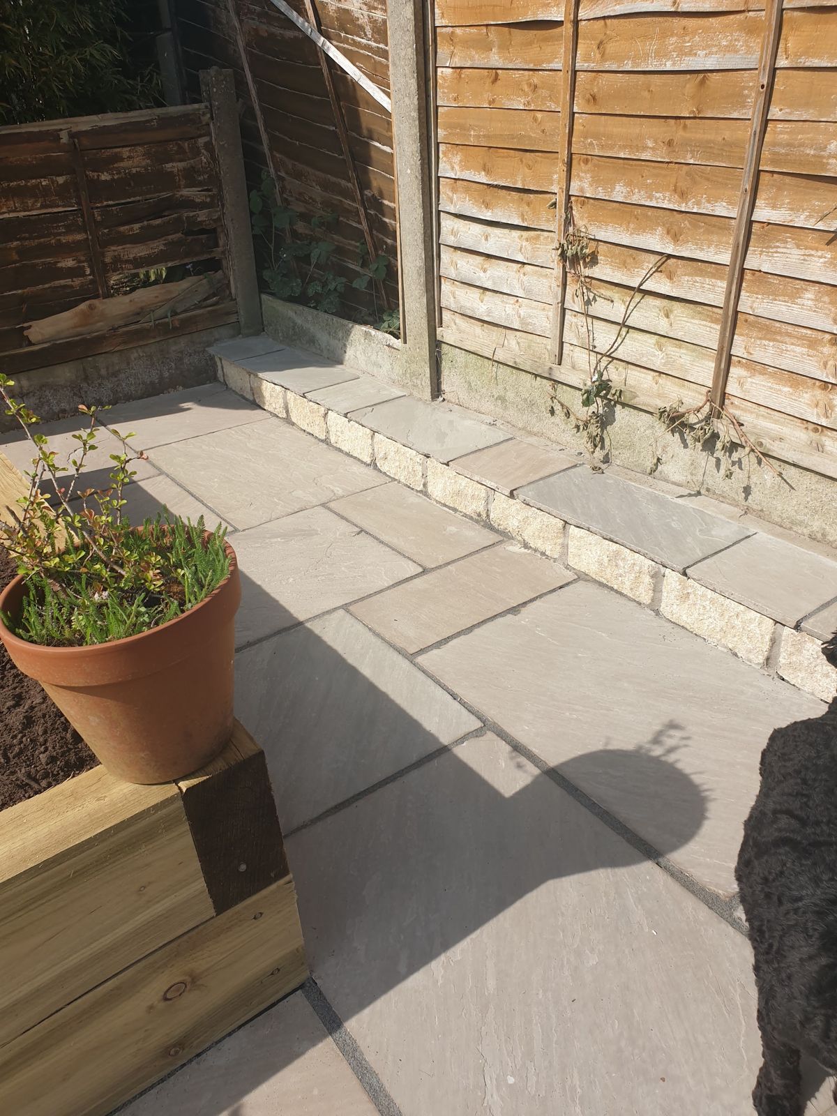 Stone patio meeting a raised sleeper bed and step edge
