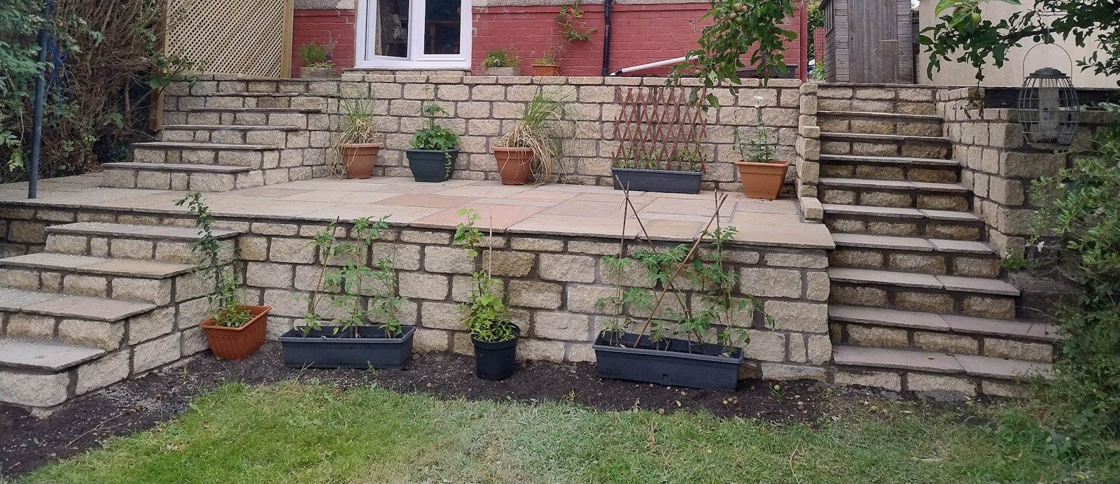 Tiered patio with natural stone walls, steps and built-in planters
